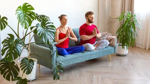 Middle-aged couple is meditating while sitting on the couch. Concept of mental Foto stock