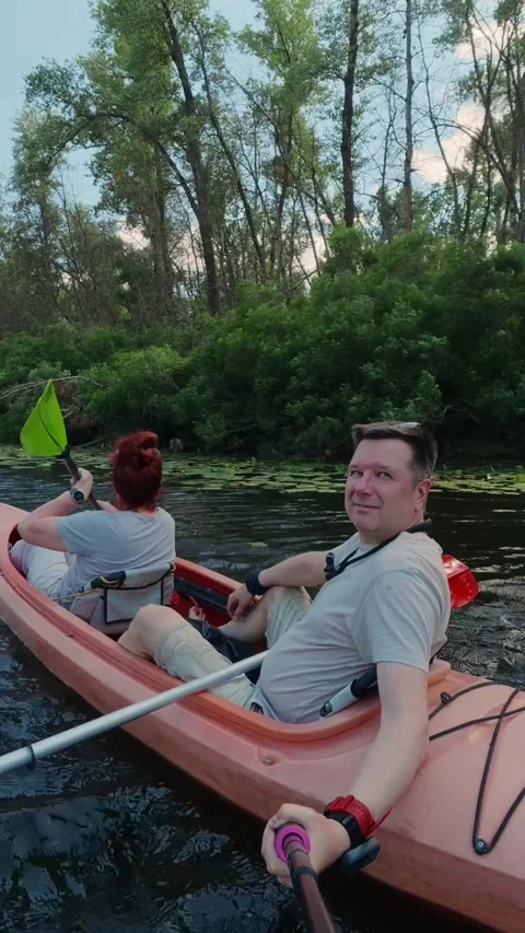 Middle-aged couple navigating tandem kayak on calm river water during summe.. Stock Footage 338990162