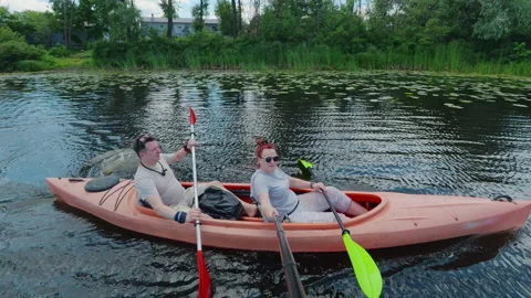 Middle-aged couple paddling orange tandem kayak on river promoting teamwork.. Stock Footage 339614172
