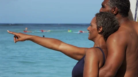 Middle-aged couple pointing on a beach. 스톡 동영상 88367588