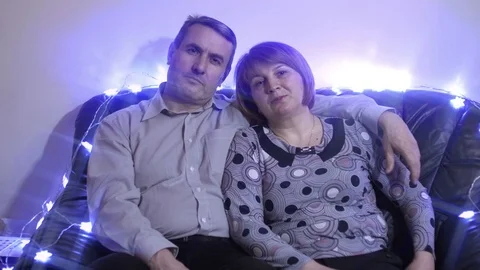 Middle aged couple relaxing on the couch smiling at camera at home in the living Stock Footage 70697725