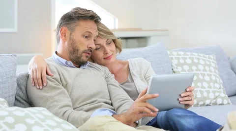Middle-aged couple relaxing in sofa and using tablet Video stock 56321802
