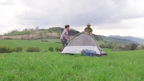 Middle-aged couple setting up camping installation, placing a touristic tent on Stock-Footage 308949055