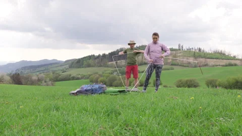 Middle-aged couple setting up camping tent on green grassy hill. Outdoor travel 스톡 동영상 331756738