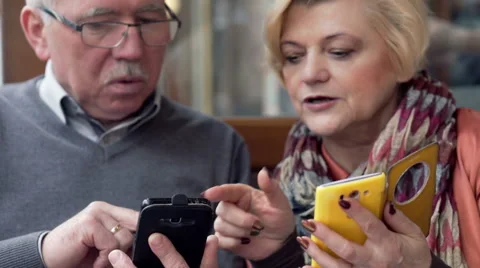 Middle aged couple showing each other something on smartphone in cafe Stock Footage 59859284