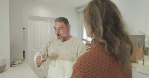 Middle-aged couple sipping wine, hearing timer and removing hot rack from oven Stock Footage 314658231