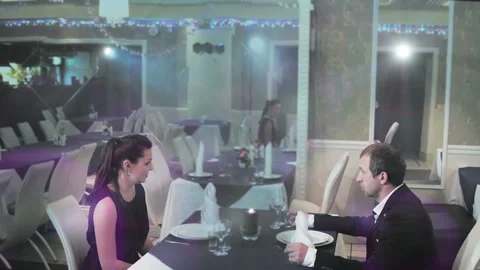 Middle-aged couple sitting at a table in a restaurant and waiting for a waiter Stock-Footage 97581272