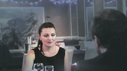 Middle-aged couple sitting at a table in a cafe woman straightens serving Stock Footage 97582344