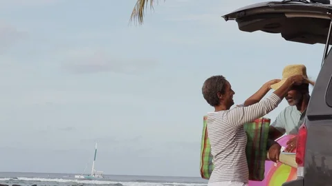Middle-aged couple unloading a car at a beach. Stockbeeldmateriaal 88370829