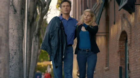 Middle-aged couple walk down the street arm in arm Stock Footage 59747676