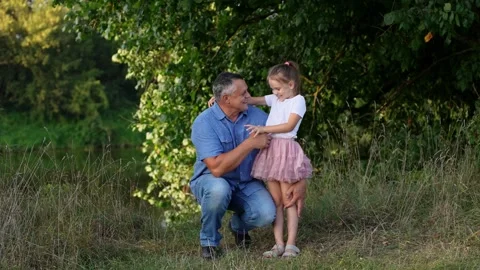 Middle aged dad squatting gently tickling and hugging cute girl creating warm Stock Footage 323535594