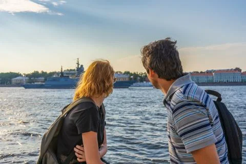 Middle-aged dark-haired man and young redhead lady on Neva river embankment l Stock Photos