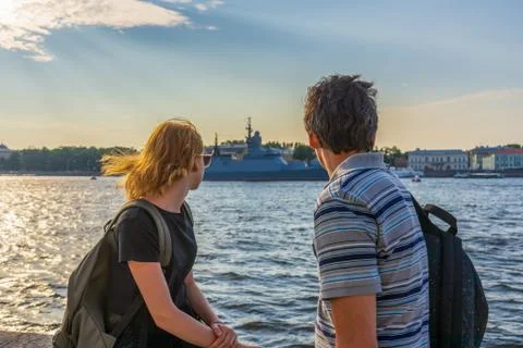 Middle-aged dark-haired man and young redhead lady on Neva river embankment l Stock Photos