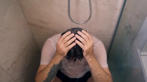 Middle-aged depressed man sitting alone in shower with wet clothes, express.. Stock Footage 342961844
