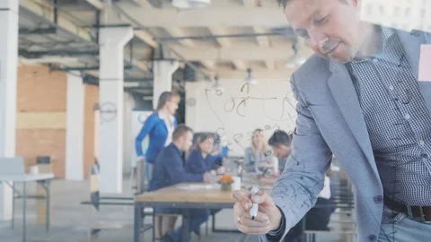 A middle-aged developer in a jacket writes formulas on a glass board with a Stock Footage 108980726