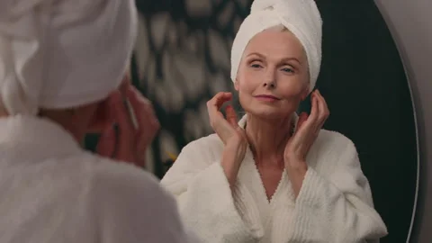 Middle-aged elderly old mature Caucasian 50s woman smile looking in mirror 스톡 동영상 246694274