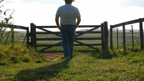 Middle-aged farmer walks down the road with the wooden gate Stock Footage 144303779
