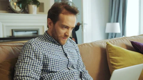 Middle aged father sitting on the sofa in the living room and working on the Stock Footage 91045776