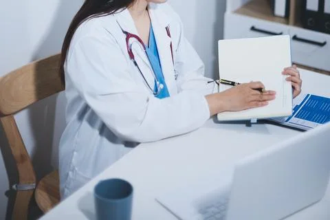 Middle aged female doctor working on laptop in doctor's room Stock Photos