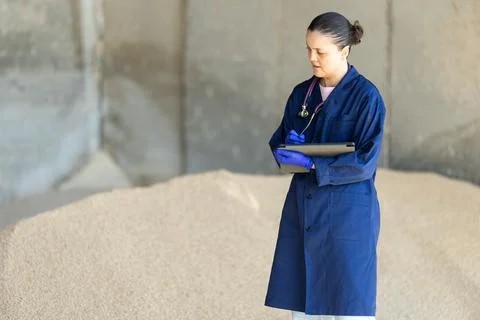 Middle-aged female farmer checking granulated feed using tabled 스톡 사진