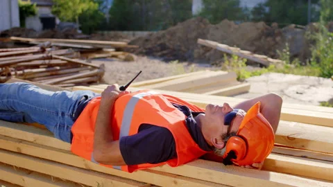 Middle-aged foreman laying down for a nap at construction site while have a Video stock 144288852