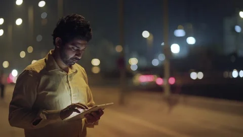 A middle aged formal Indian man using digital tablet against moving city traffic Stock Footage 330956208