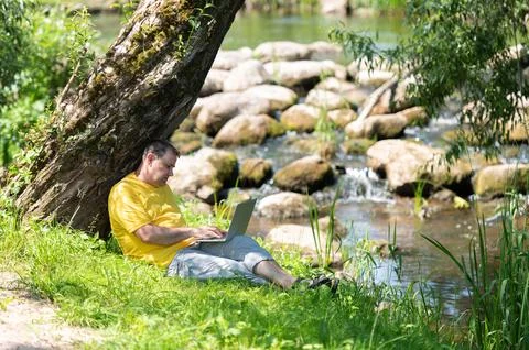Middle aged freelancer using a laptop computer while working in beautiful nat Stock Photos