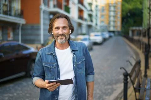 Middle aged grey haired freelancer man hold digital tablet in hands having a Stock Photos