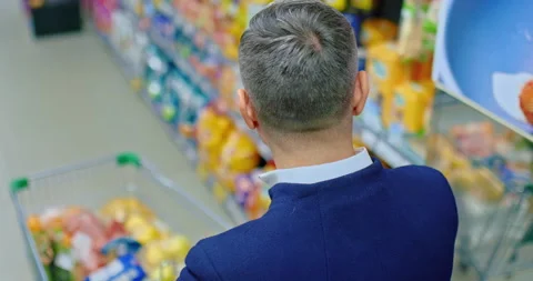Middle-aged grey-haired man shopping in supermarket, , walk in trading hall with Stock Footage 238687090
