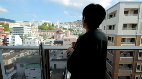 Middle aged guy looks outside from balcony. Silhouette. Dolly in. 25P. Stock Footage 224899082