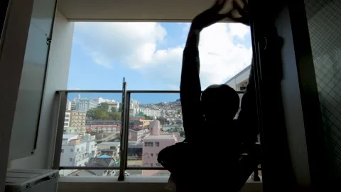 Middle aged guy sit and relax on balcony. Silhouette. Dolly to left. 25P. Stock Footage 224898957