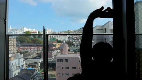 Middle aged guy sit and relax on balcony. Silhouette. Dolly to right. Stock Footage 224902934