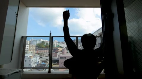 Middle aged guy sit and relax on balcony. Silhouette. Dolly to left. Stock Footage 224903189