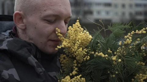 Middle-aged guy sniffs mimosa, he has problems with the skin of the face Stock Footage 127561761