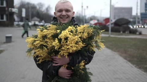 Middle-aged guy on the street with mimosa flowers, smiling, giving flowers Stock Footage 127561857