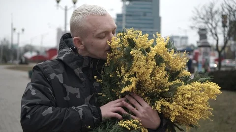 Middle-aged guy on the street with mimosa flowers Stock Footage 127562234