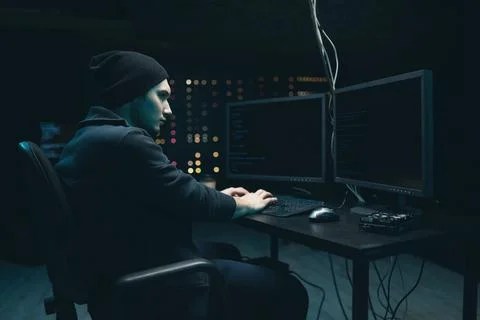 Middle aged hacker making cryptocurrency fraud using virus software and computer Stock Photos