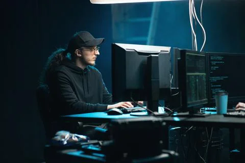 Middle aged hacker making cryptocurrency fraud using virus software and computer Stock Photos