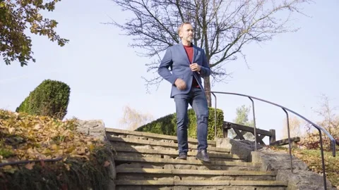 A middle-aged handsome Caucasian man walks down a stone staircase in a rural 库存影片 201776953