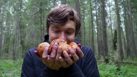 Middle aged happy man smiles at the camera and shows mushrooms in autumn dense Stock Footage 159608960