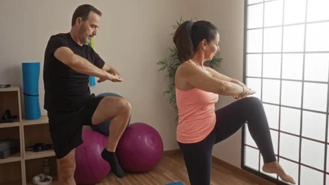 Middle-aged hispanic couple exercising indoors at a gym with gym balls, mat.. Stock Footage 303416824