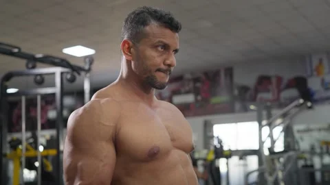 Middle aged Indian male performs a single arm dumbbell curl in a modern gym Stock Footage 341856416