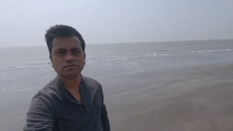 Middle aged indian man talking a selfie and revolving around at an empty beach Stock Footage 149386376