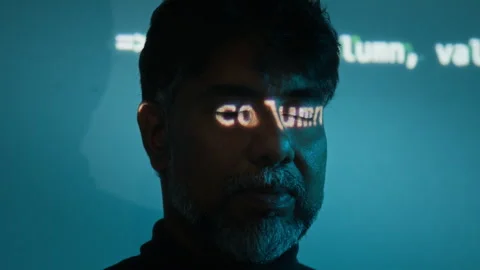 Middle Aged Indian Programmer Standing under Code Projection in Studio Stock Footage 347300069