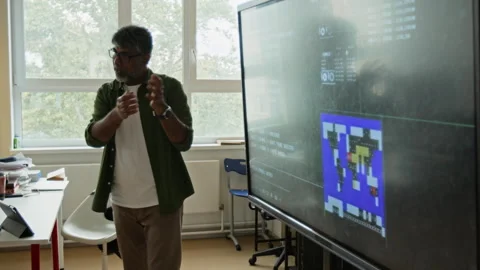 Middle Aged Indian Teacher Explaining Coding on Interactive Screen Stock Footage 342817980