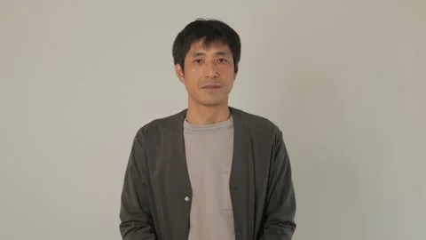 Middle aged Japanese man opens his eyes and stares the camera. Emotionless. 25P. Stock Footage 224899313