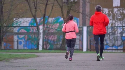 Middle-aged of joggers is running around the stadium, slow motion Stock Footage