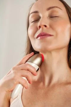 Middle aged lady doing led therapy neck skin massage using anti-aging electri Foto stock