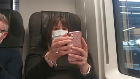 Middle-aged lady looking at her phone wearing a face mask on the eurostar Stock Footage 171301514
