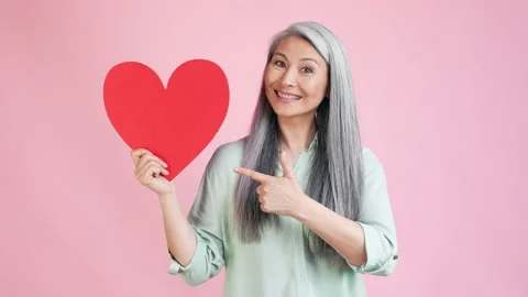 Middle aged lady point big heart win gift isolated pastel color background Stock Footage 165347331